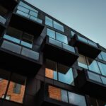 Low angle view of modern residential building facade in Copenhagen, showcasing glass balconies and reflections.