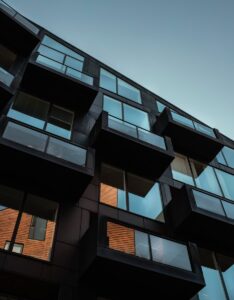 Low angle view of modern residential building facade in Copenhagen, showcasing glass balconies and reflections.
