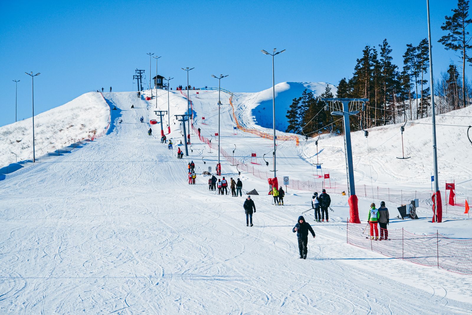 People enjoy a sunny winter day skiing and snowboarding at a bustling ski resort.